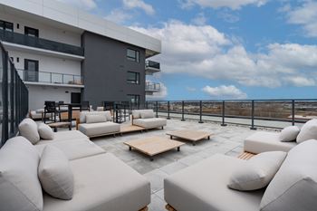 A modern outdoor seating area with white cushioned furniture and a view of the city